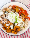 Butternut Squash Fajita Bowl - Roasted butternut squash, bell peppers, caramelized onions, and fajita-spiced chicken over brown rice, finished with lime crema, cotija