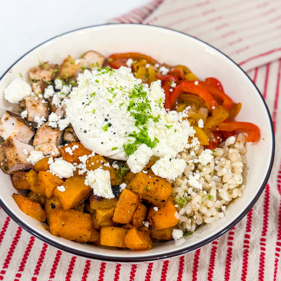 Butternut Squash Fajita Bowl - Roasted butternut squash, bell peppers, caramelized onions, and fajita-spiced chicken over brown rice, finished with lime crema, cotija