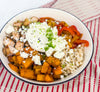 Butternut Squash Fajita Bowl - Roasted butternut squash, bell peppers, caramelized onions, and fajita-spiced chicken over brown rice, finished with lime crema, cotija