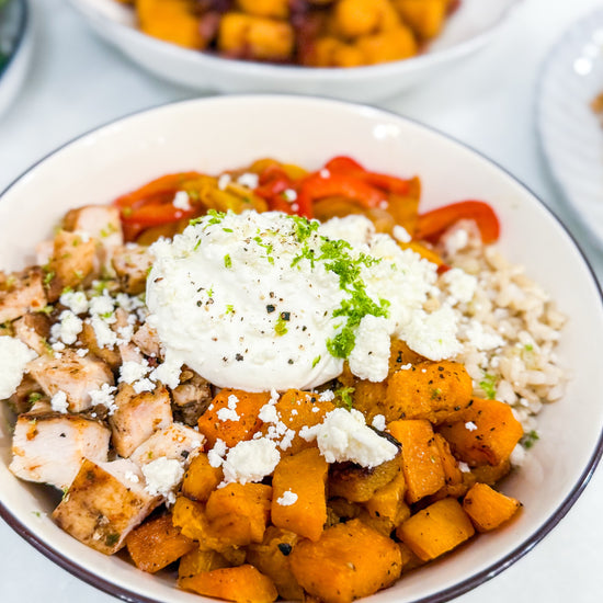 Butternut Squash Fajita Bowl - Roasted butternut squash, bell peppers, caramelized onions, and fajita-spiced chicken over brown rice, finished with lime crema, cotija