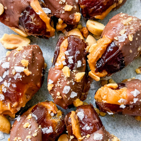 Date Snickers - Date stuffed with peanut buttered drizzled with chocolate and topped with chocolate peanuts and sea salt