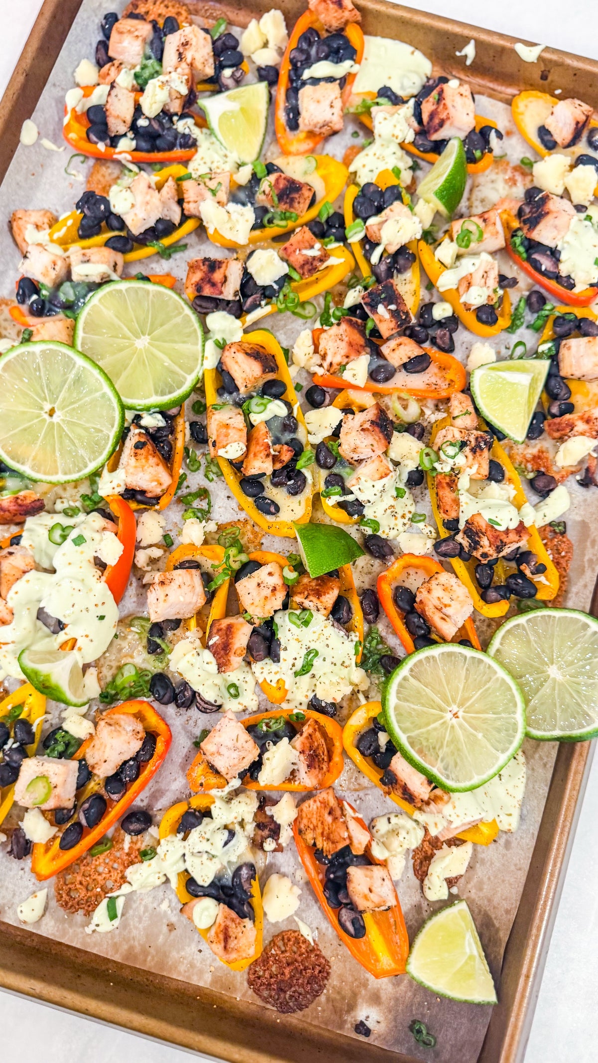 Eat Fit Pepper Nachos - Mini sweet peppers topped with chili-lime chicken, black beans, white cheddar, and green onions, finished with avocado sour cream and fresh lime